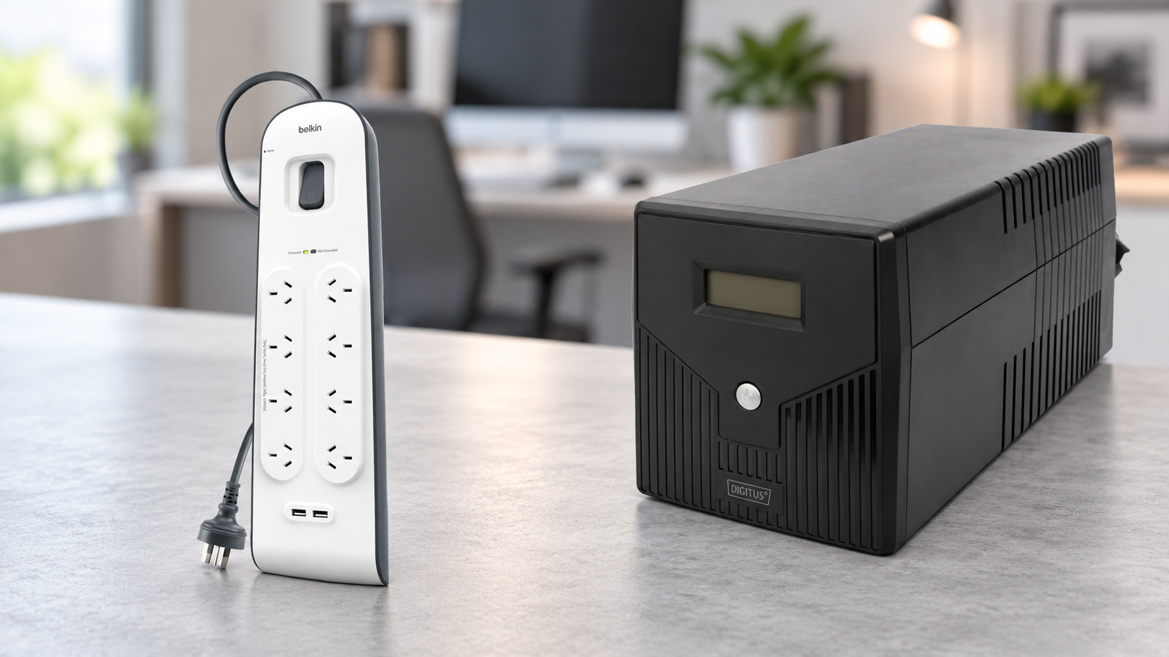 Belkin surge protector power board and Digitus UPS on a desk with a blurred home-office background.