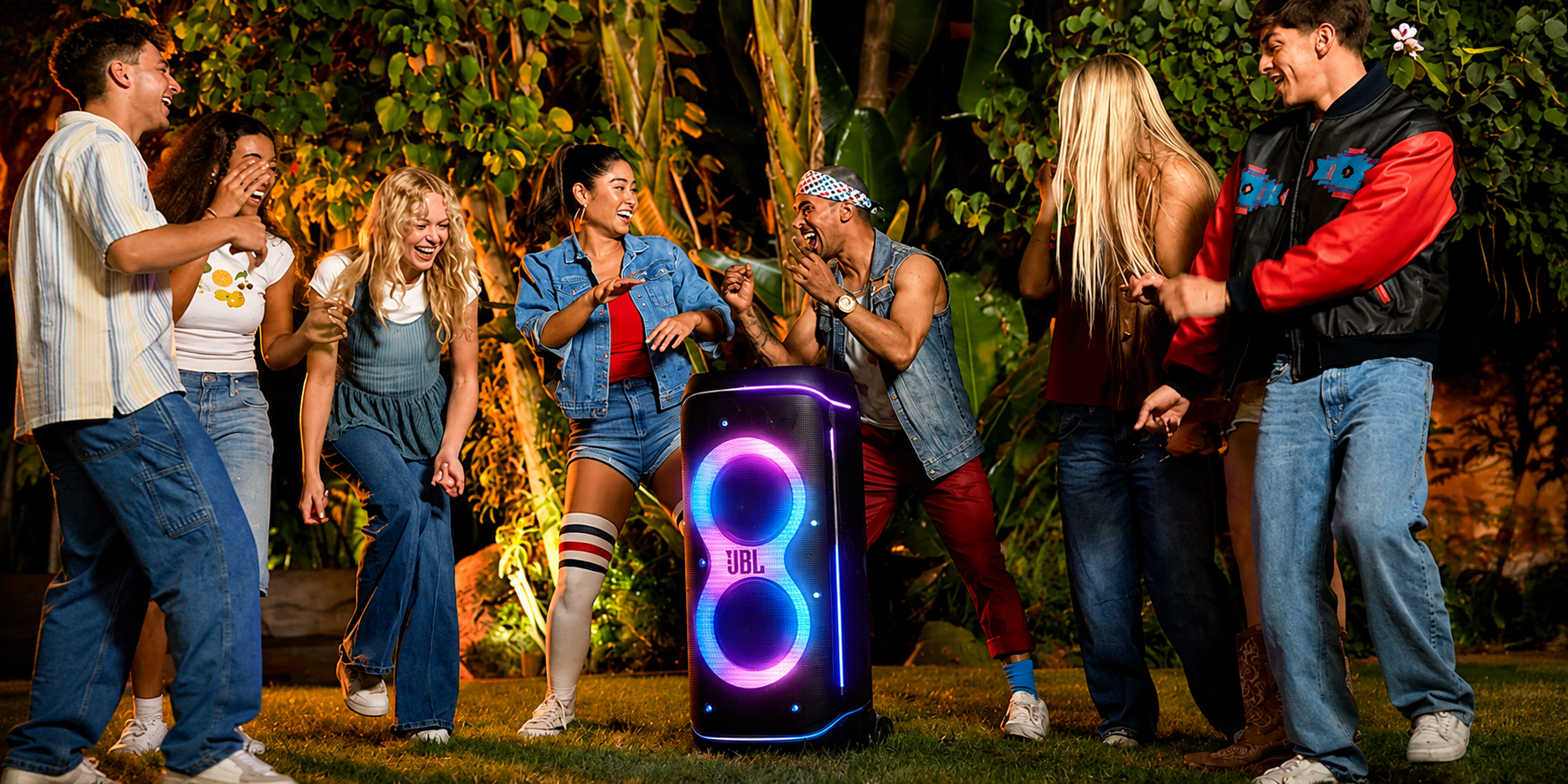 Group of friends dancing outdoors around a JBL PartyBox speaker with LED lights - Party Speakers at Tech Supply Shed NZ