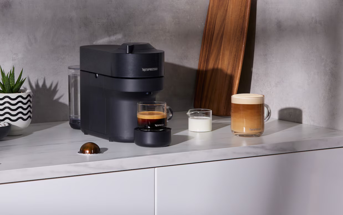 Black Nespresso coffee machine with espresso, milk and latte on a modern kitchen bench in New Zealand.