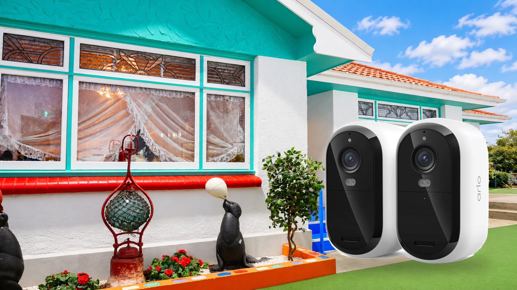 Two Arlo security cameras in front of Canterbury Museum’s recreated Pāua Shell House from Bluff, with an illustrative blue-sky background - Security Cameras at Tech Supply Shed NZ