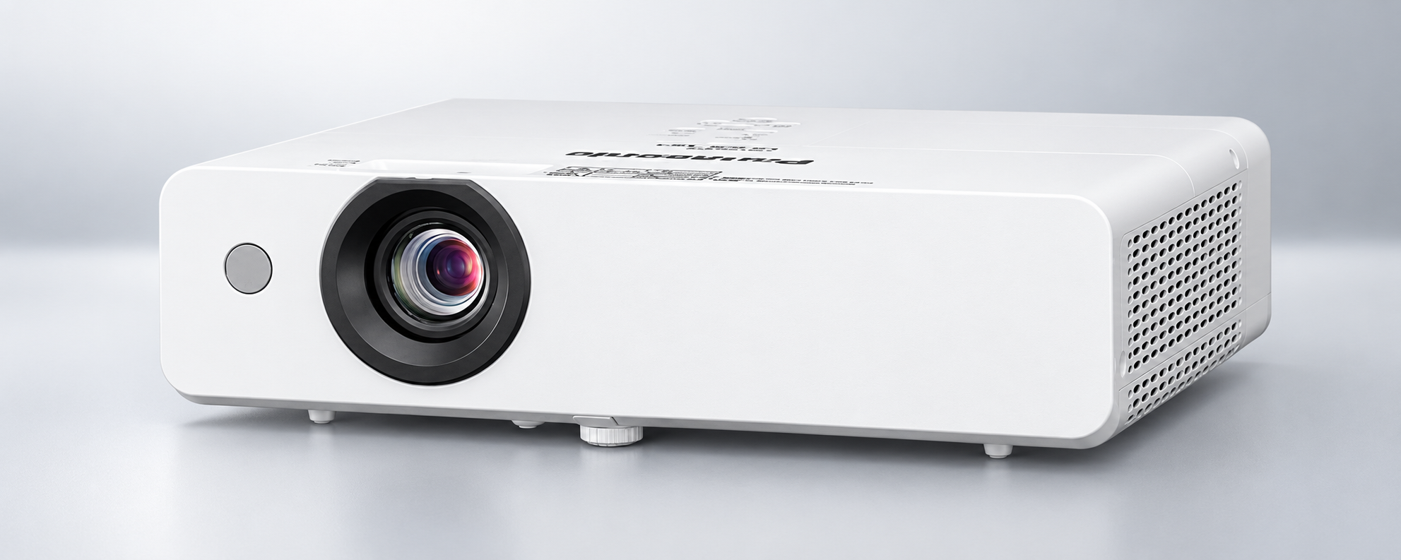 White projector with front lens and ventilation grilles on a grey surface - Commercial Projectors at Tech Supply Shed NZ