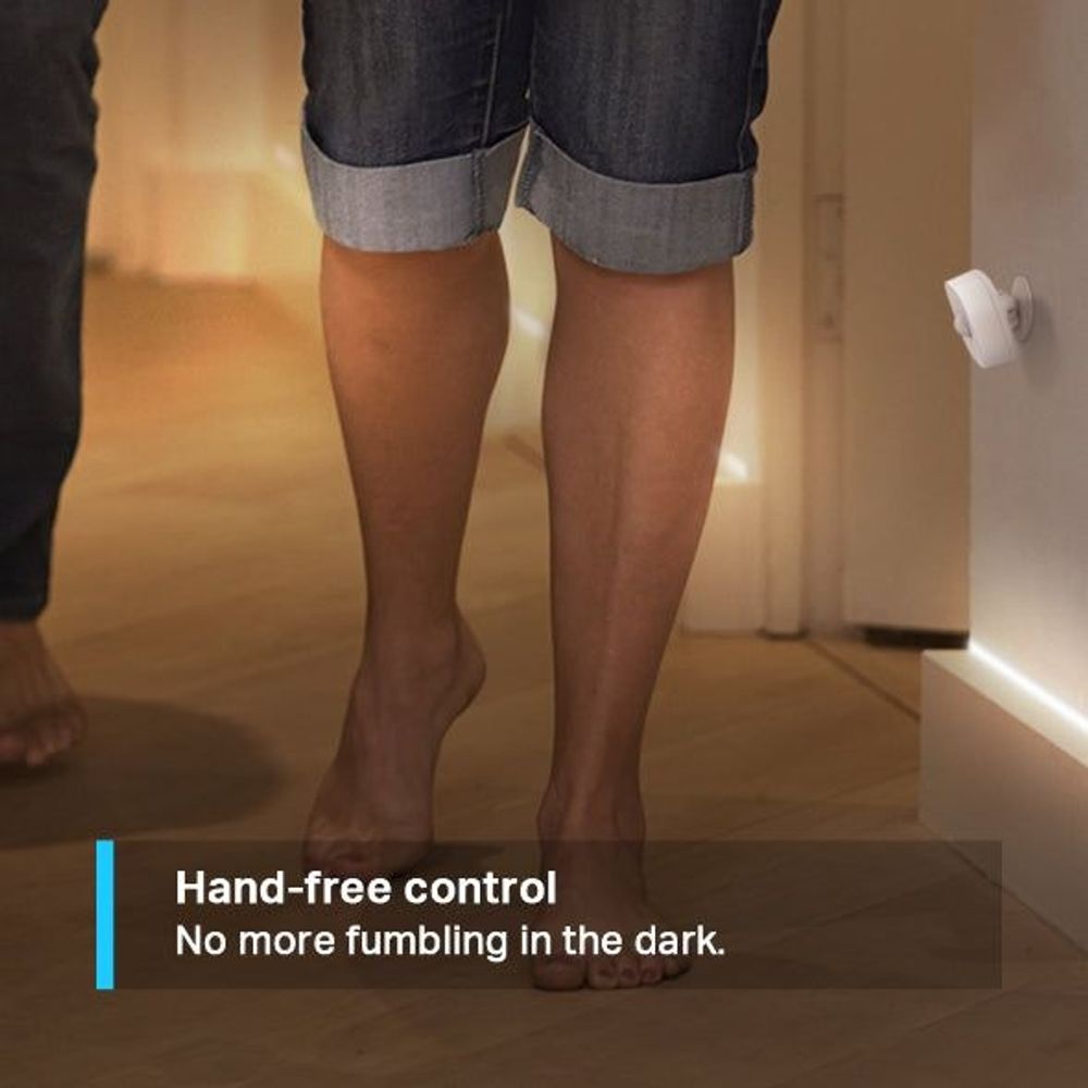 White TP-Link Tapo smart motion sensor mounted on a wall near hallway