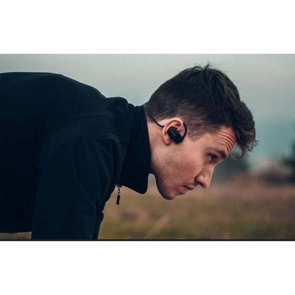 Black sport earphones worn by a person, showing one earbud and neckband