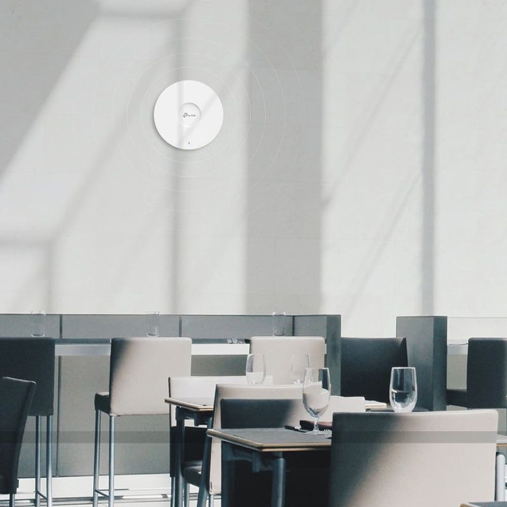 Small white ceiling access point installed on a meeting room ceiling