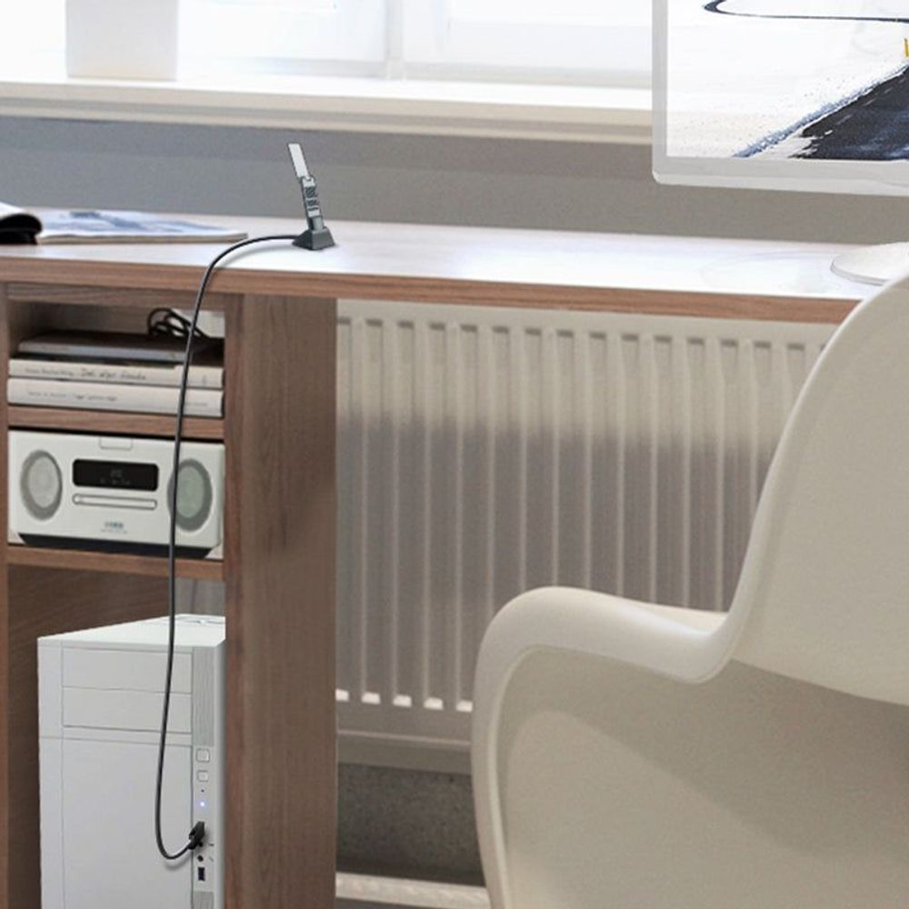 Wireless USB adapter antenna plugged in near a desk computer and router