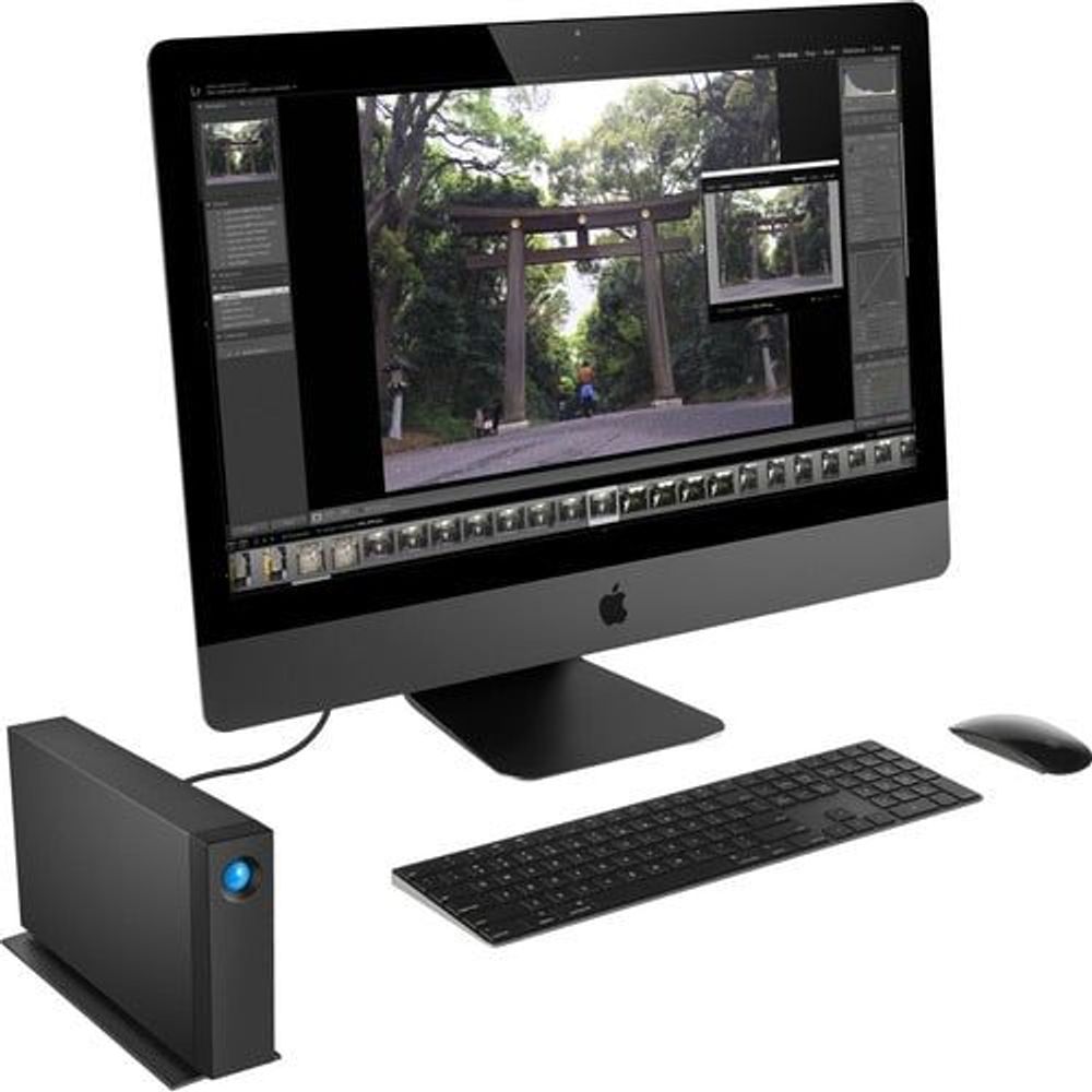Black desktop external hard drive with blue LED on desk next to keyboard