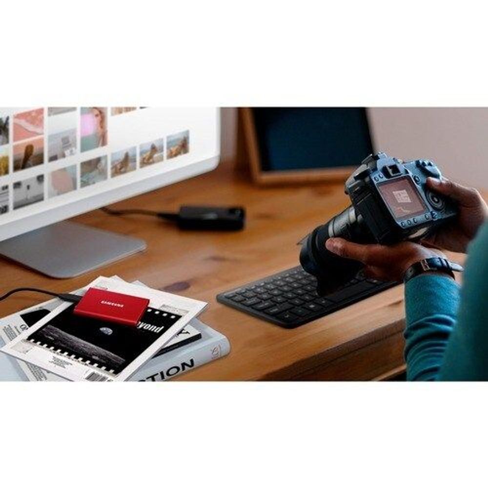 Red Samsung Portable SSD T7 connected with a cable on a desk