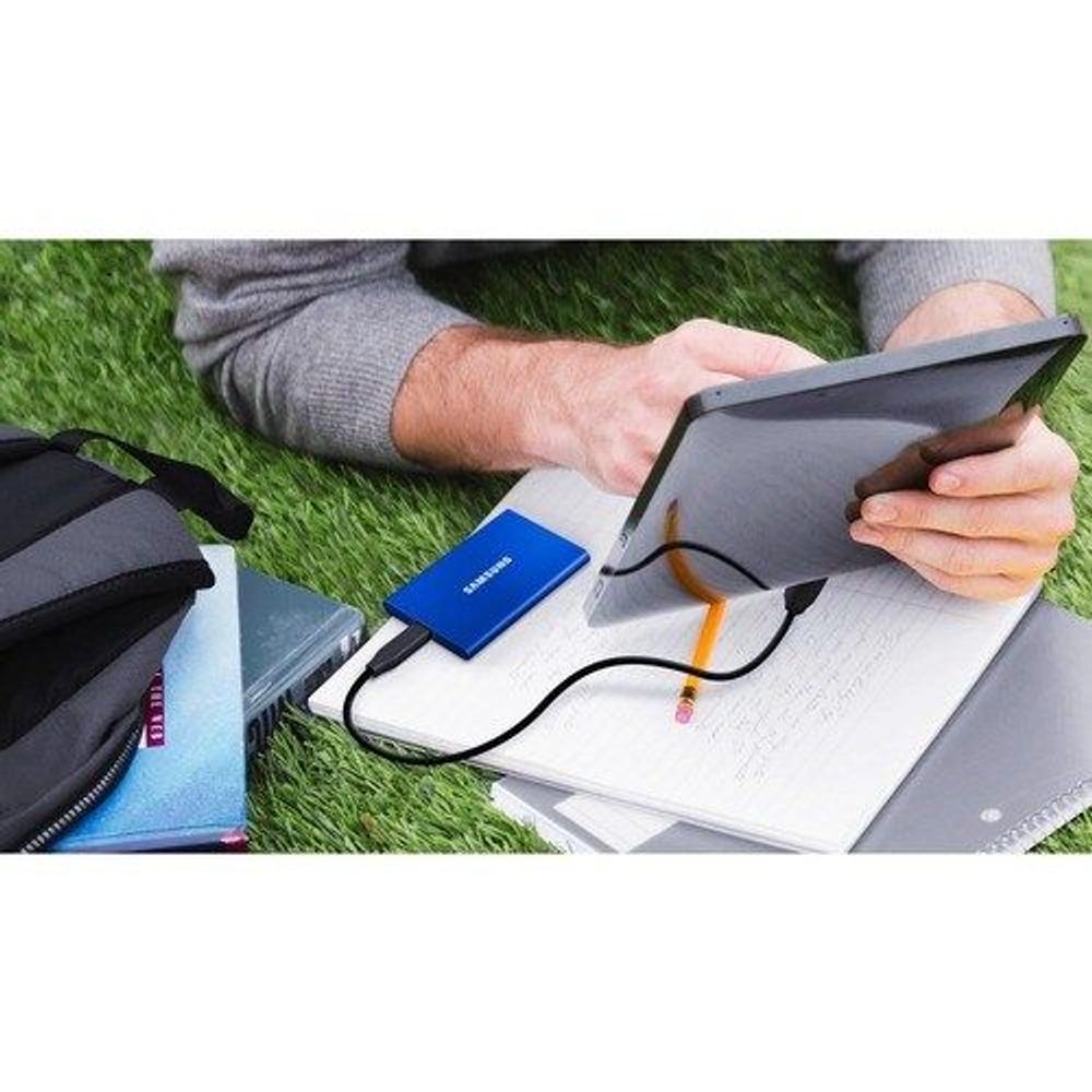 Blue Samsung Portable SSD T7 external drive with USB cable connected on a notebook.