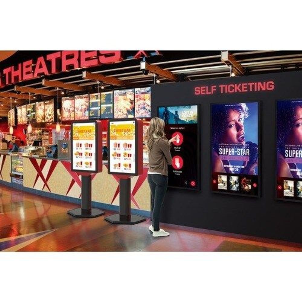 Touchscreen digital signage display mounted on wall in venue, showing booking interface