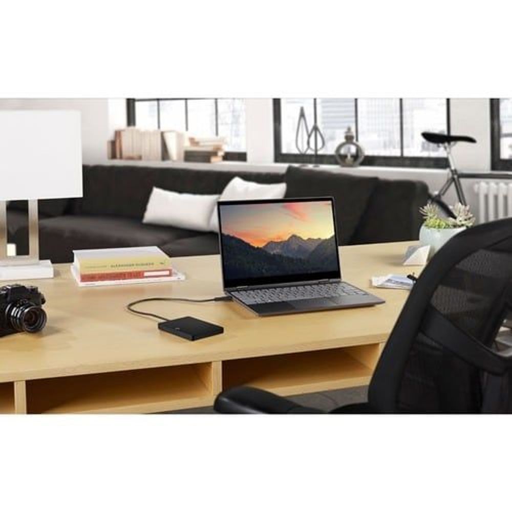 Black portable hard drive connected to a laptop on a desk