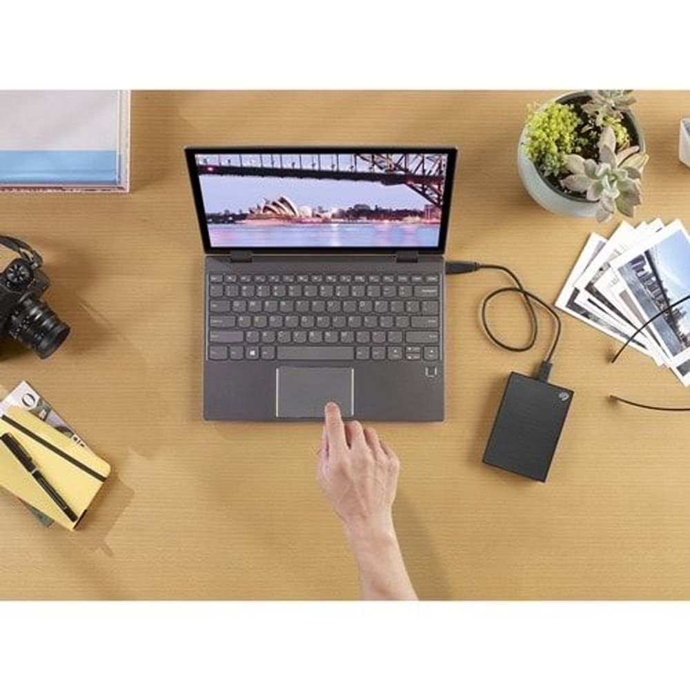Black portable hard drive connected to laptop on a desk