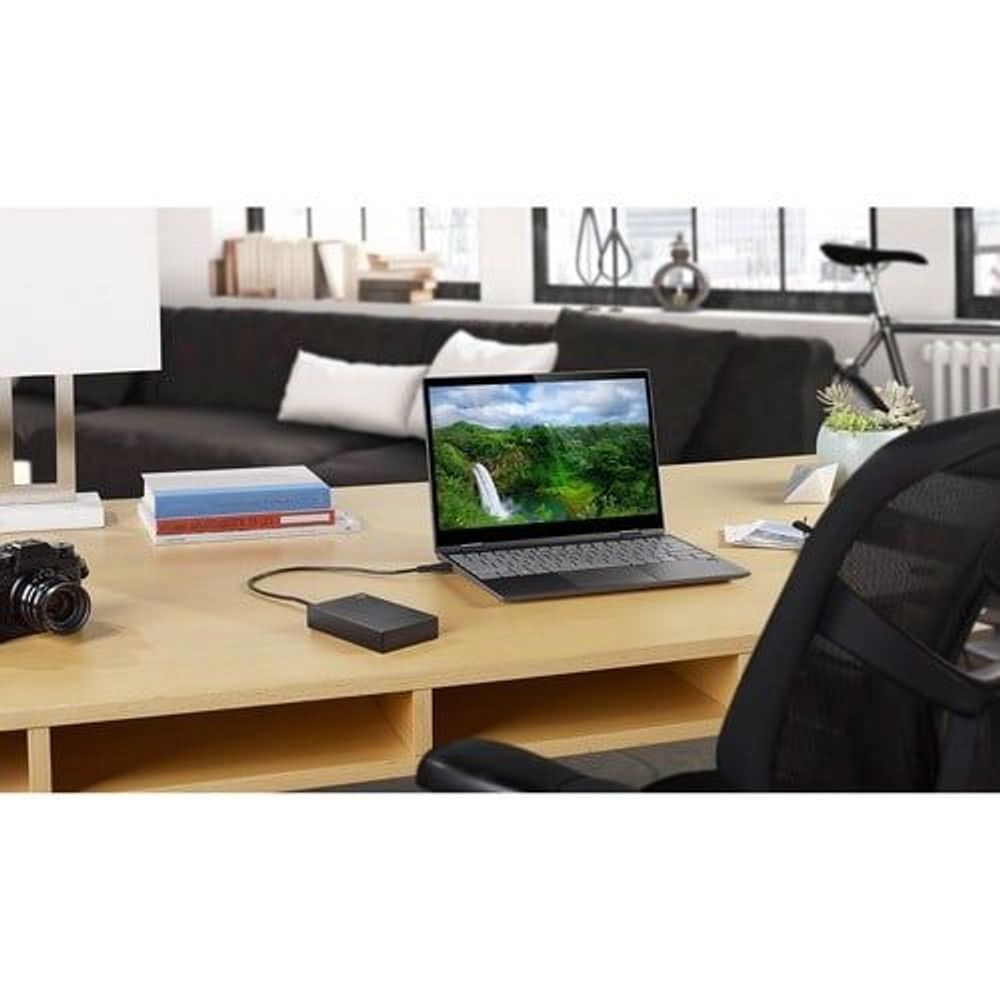 Portable black hard drive connected to laptop for file storage and transfer