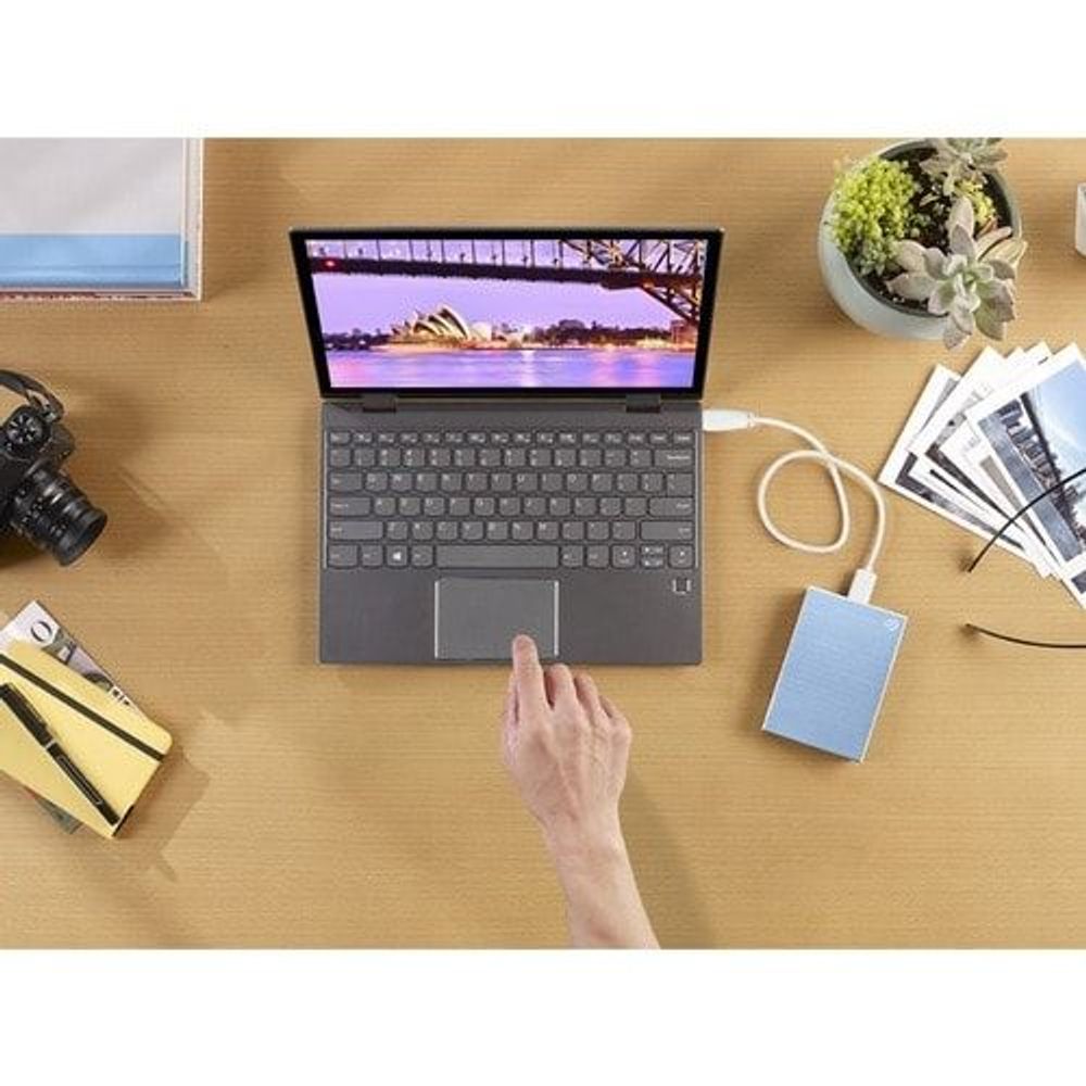 Light blue portable hard drive with USB cable connected to a laptop