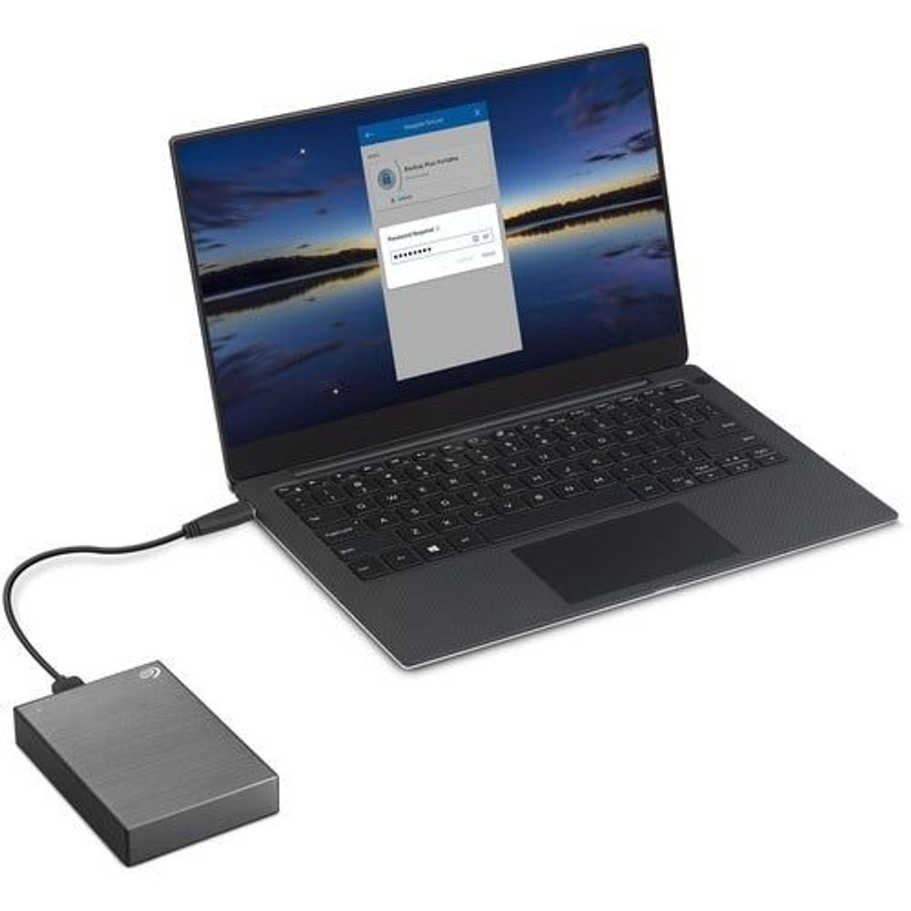 Space gray portable hard drive plugged into a laptop via USB cable