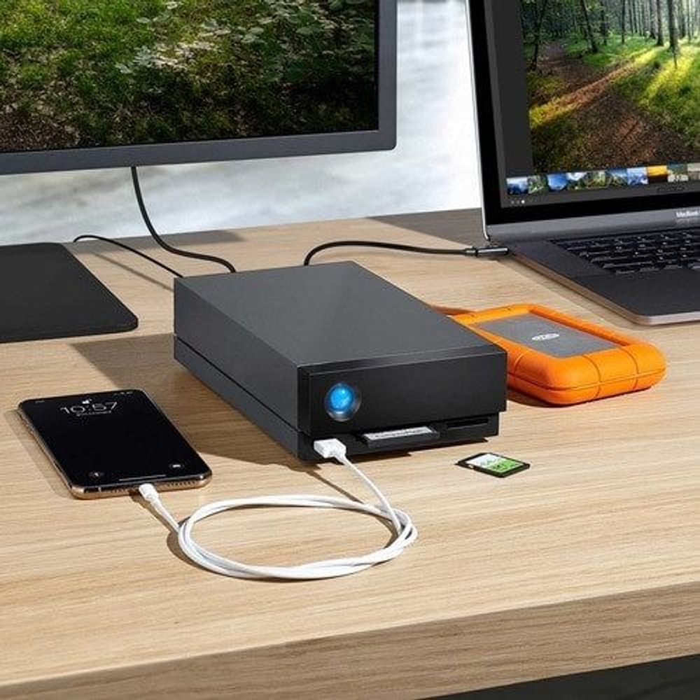 Black desktop external hard drive with blue LED and connected cables on desk