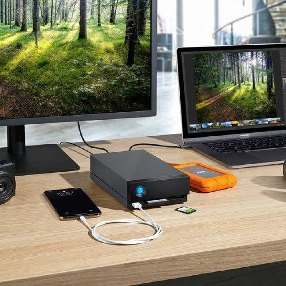 Black desktop external hard drive with blue LED on desk with connected cables