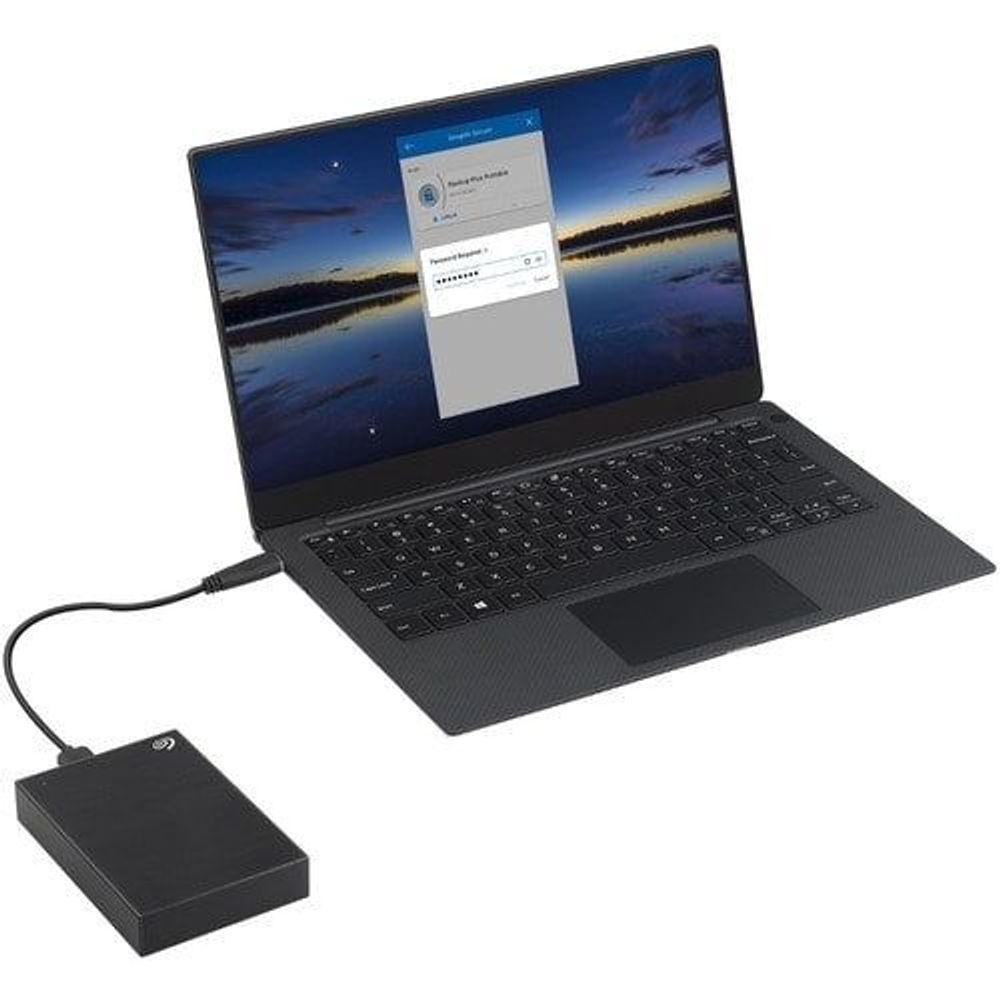 Black Seagate external hard drive connected by cable to a laptop
