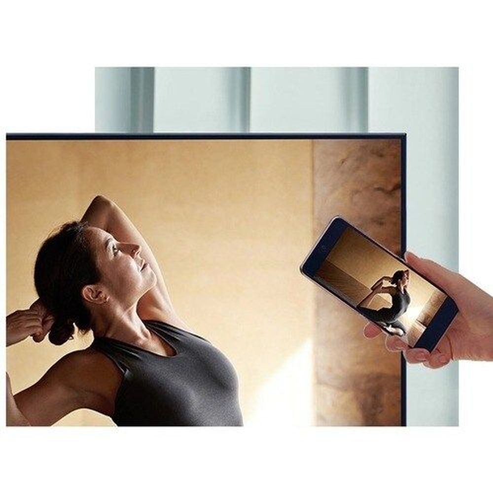Samsung 50-inch smart LED-LCD TV on a stand, showing a person using a smartphone.