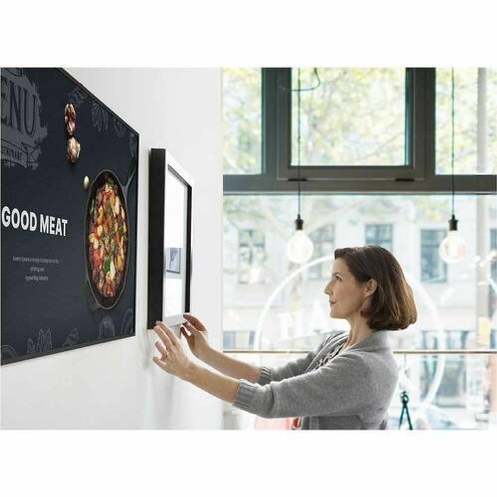 Wall-mounted Samsung digital signage display with person adjusting content on screen