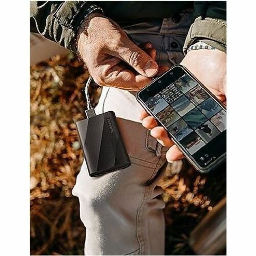 Black portable SSD being plugged in outdoors from a hand-held device