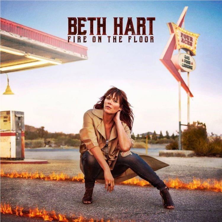Music album cover featuring Beth Hart kneeling near flames by road sign