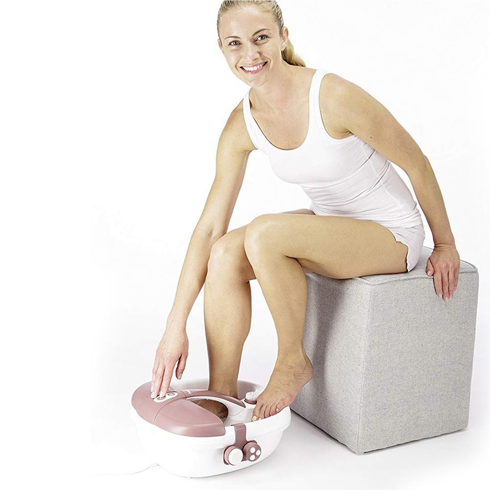 Pink foot spa used on a seated person’s feet next to the base unit