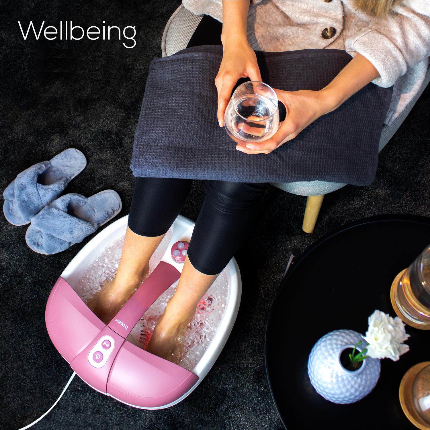 Pink foot spa soaking feet with visible water bubbles and massage zone