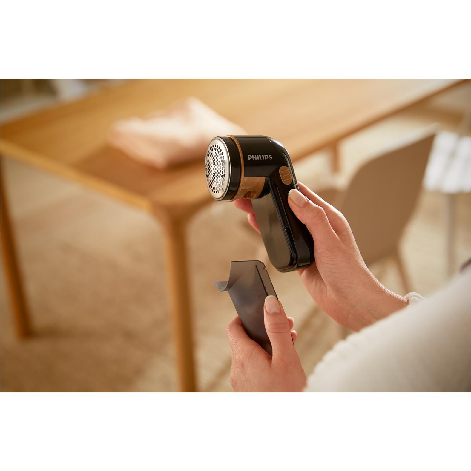 Handheld fabric shaver in use on upholstery fabric