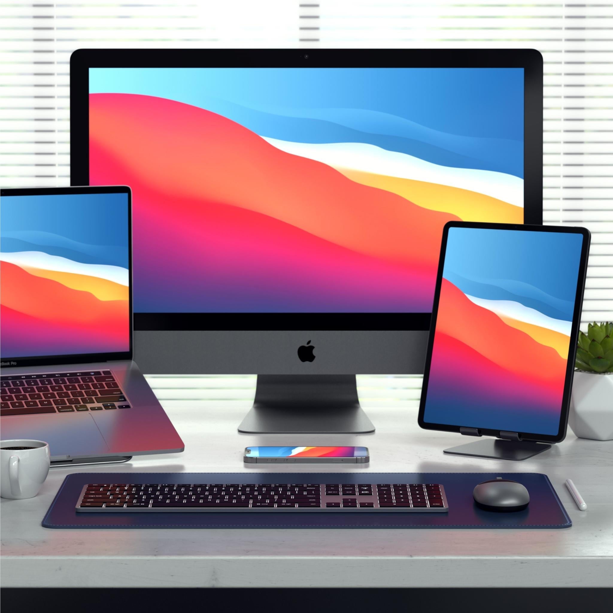 Backlit Bluetooth Mac keyboard on desk in front of desktop monitor setup