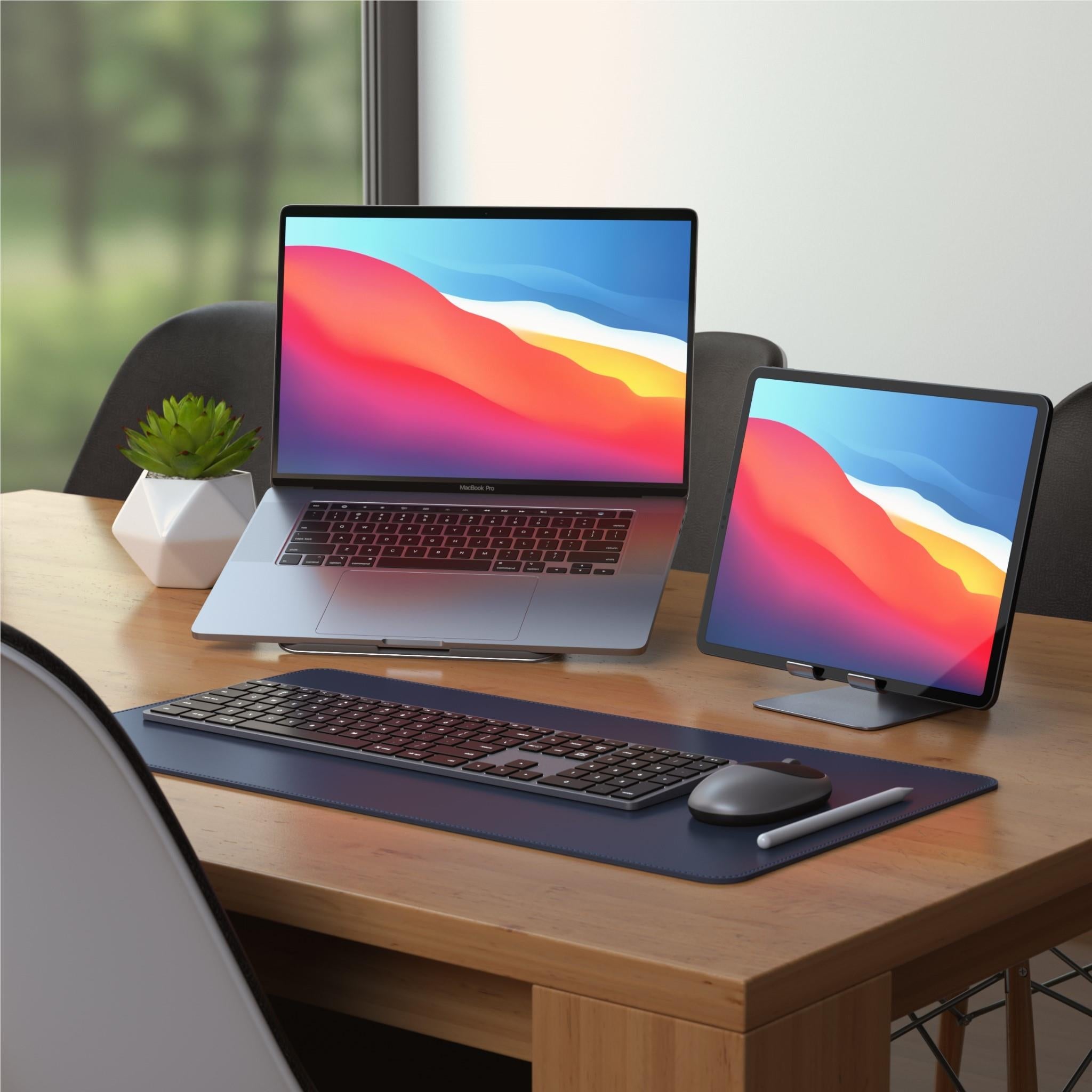 Backlit Bluetooth Mac keyboard on desk with laptop and tablet nearby
