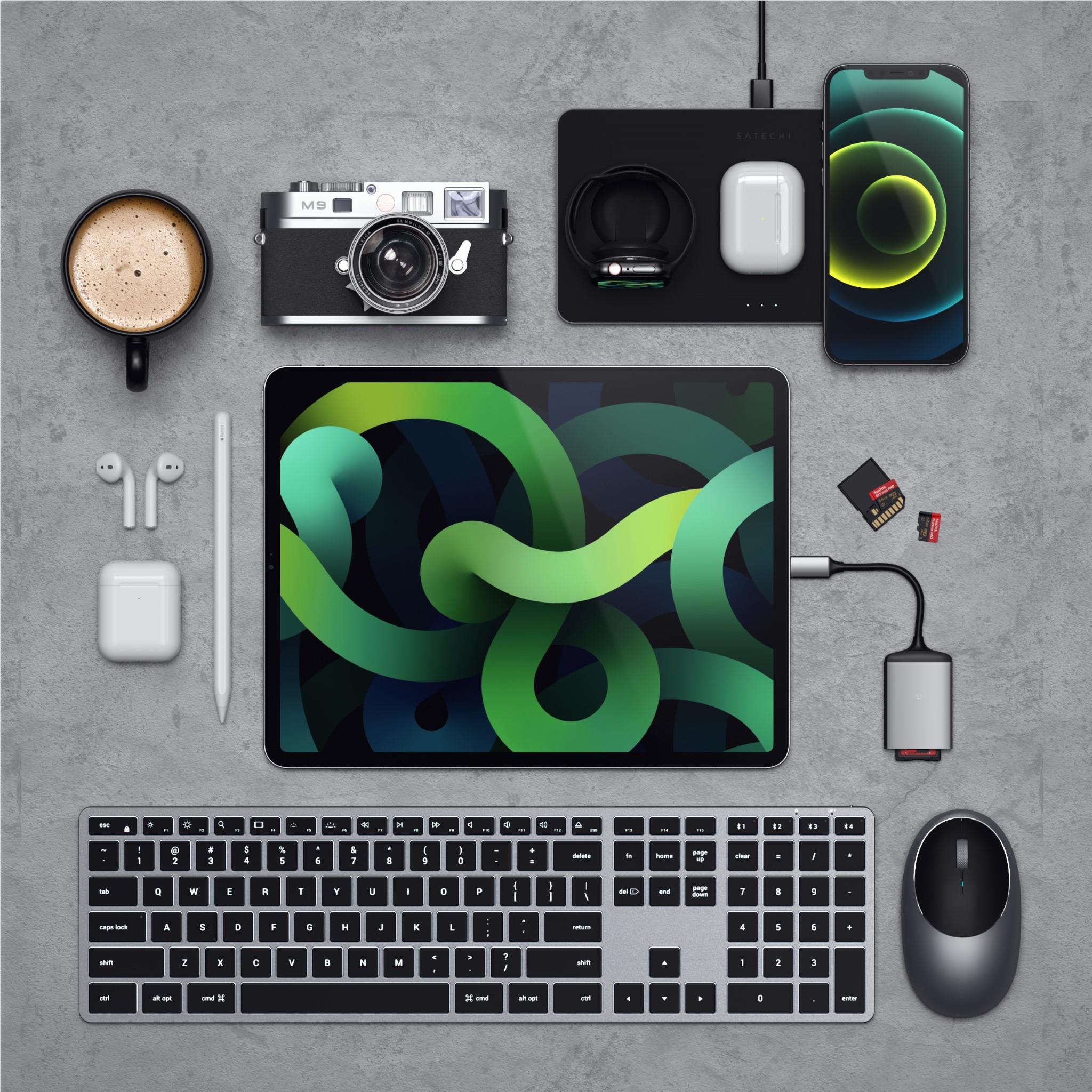 Backlit Bluetooth Mac keyboard in overhead tech flat lay with accessories