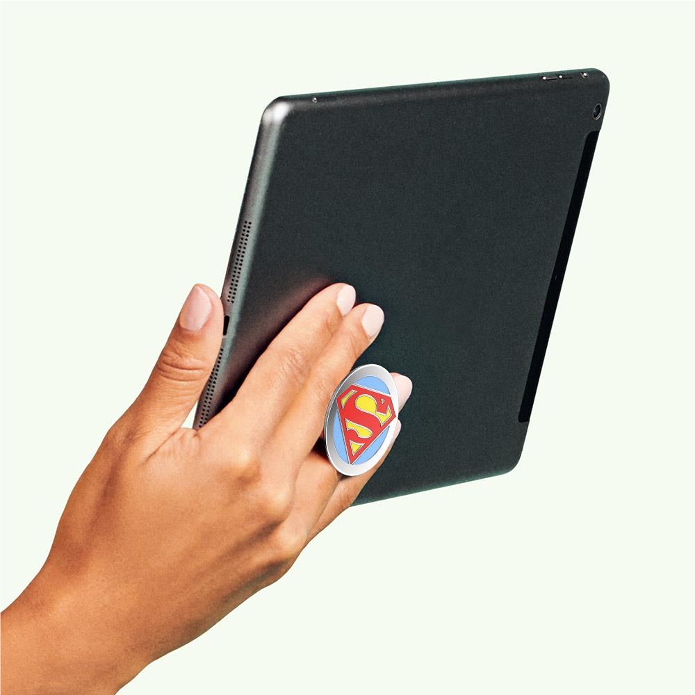 Round Superman logo PopGrip pressed on back of black phone
