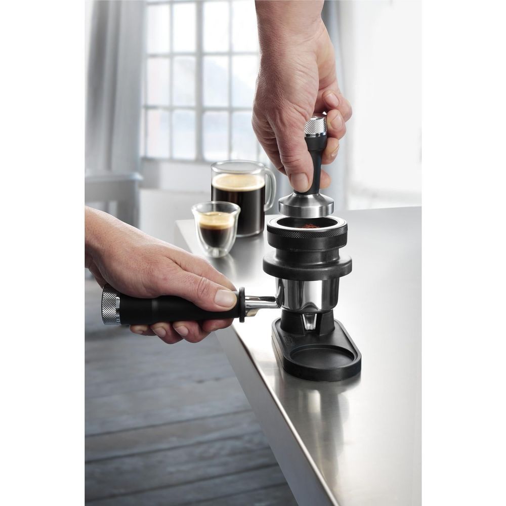 Hands filling an espresso cup using a manual lever espresso machine filter holder