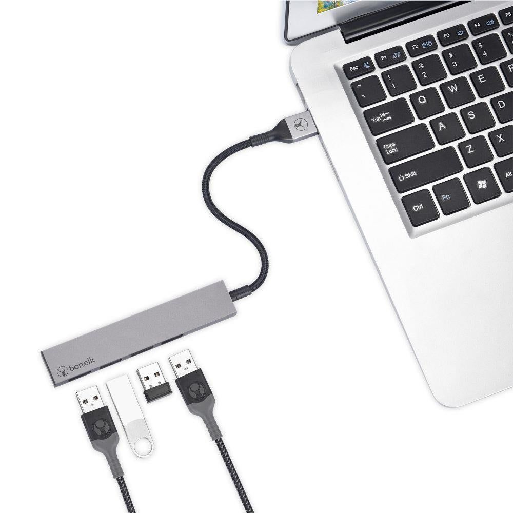 Space grey 4-port USB hub connected to a laptop with cables plugged into ports