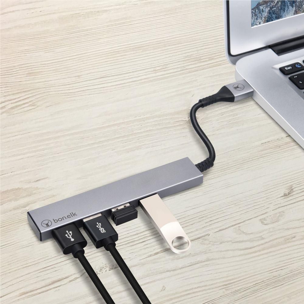 Space grey 4-port USB hub on desk with cables plugged into the blue ports