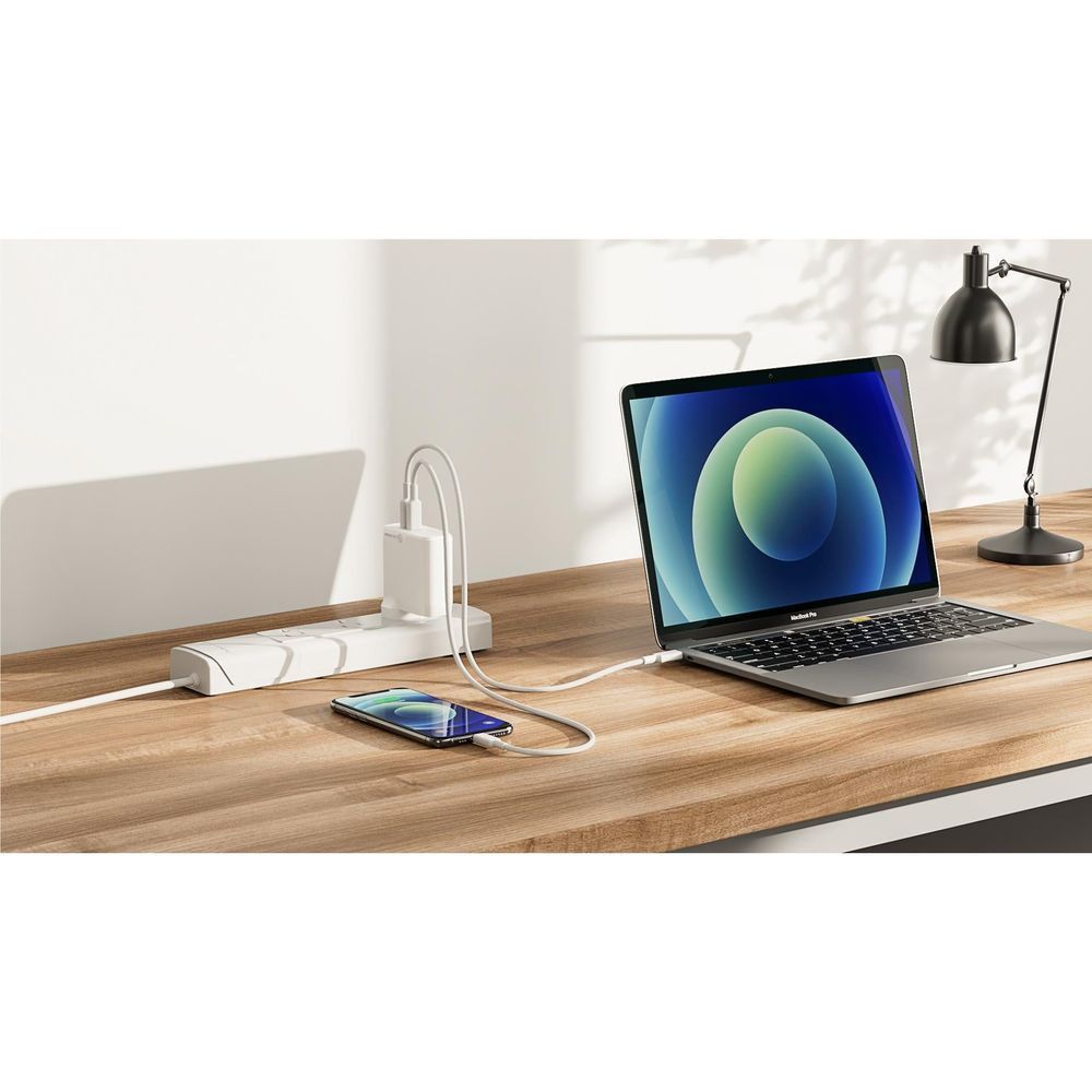White USB-C wall charger with cable charging a smartphone and laptop