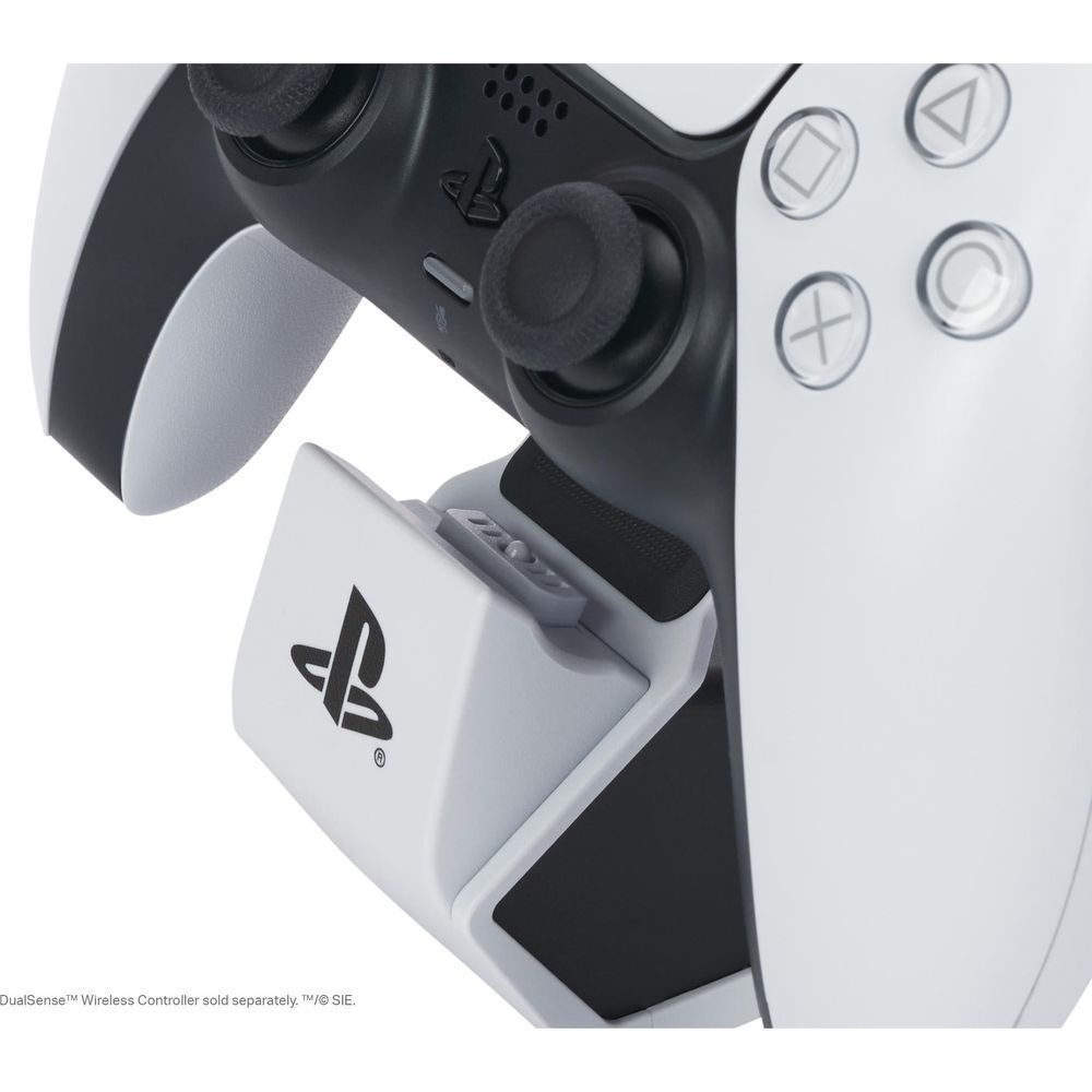 White charging dock supporting a controller with black charging contacts, close-up
