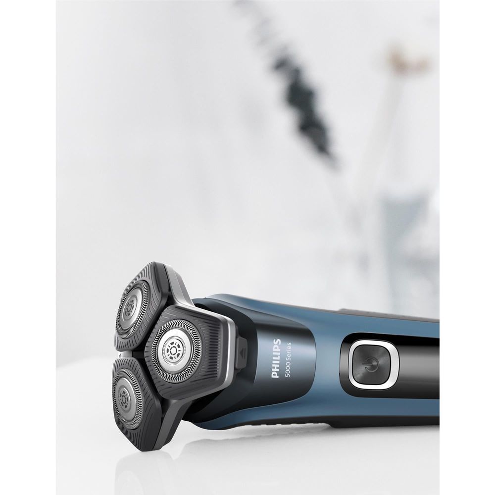 Blue electric shaver with three foil heads, close-up of head and button