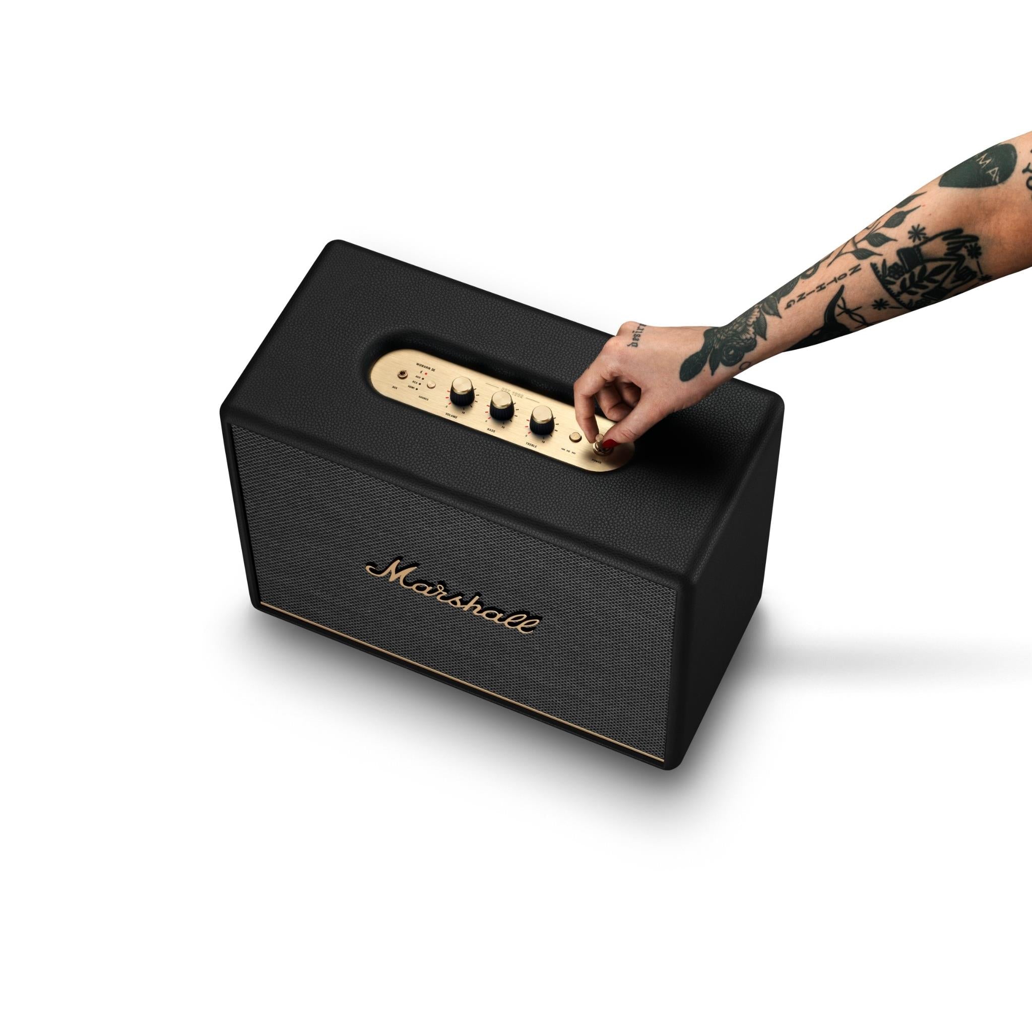 Black portable speaker being lifted by a hand at the top control panel