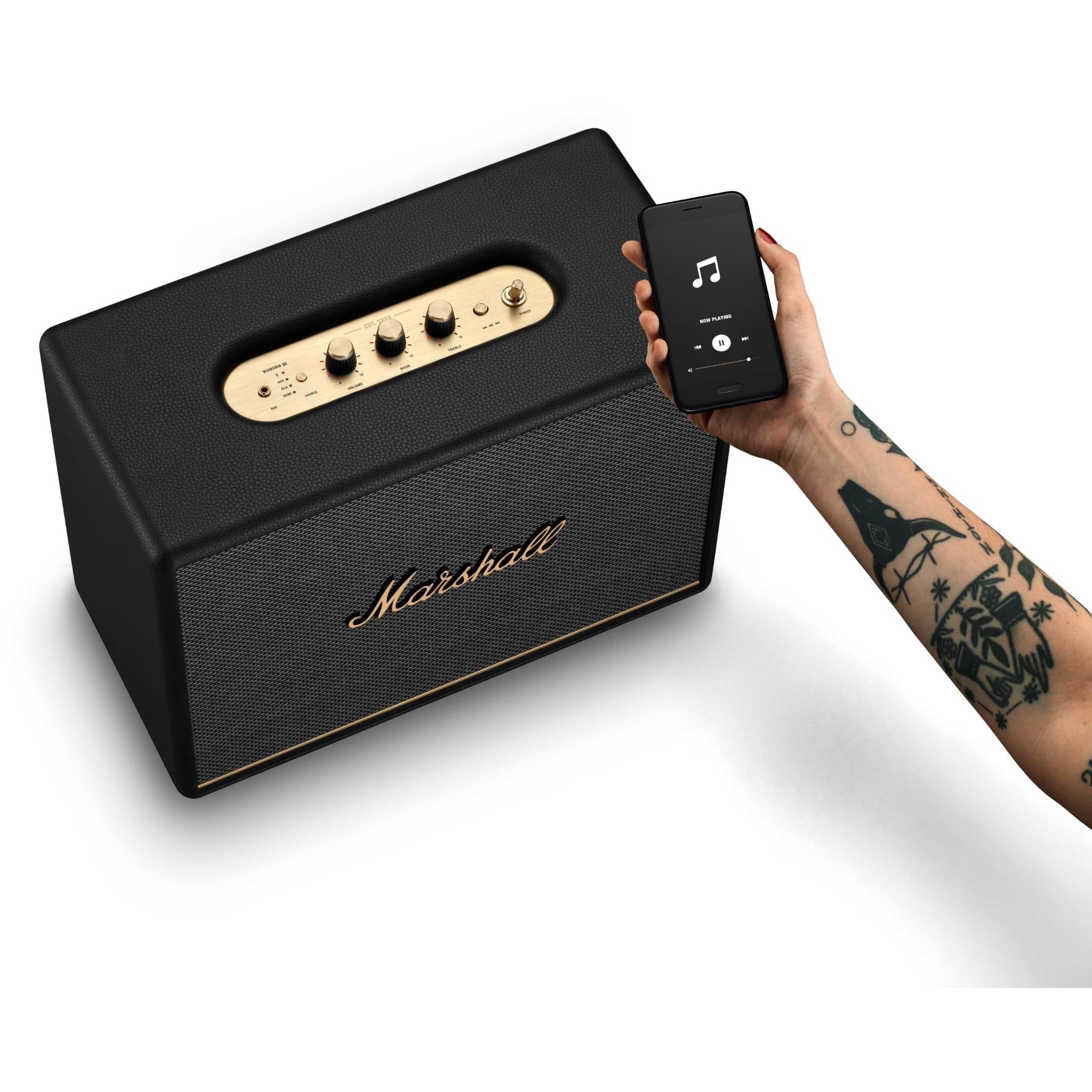 Black Bluetooth speaker with phone held near the top control panel