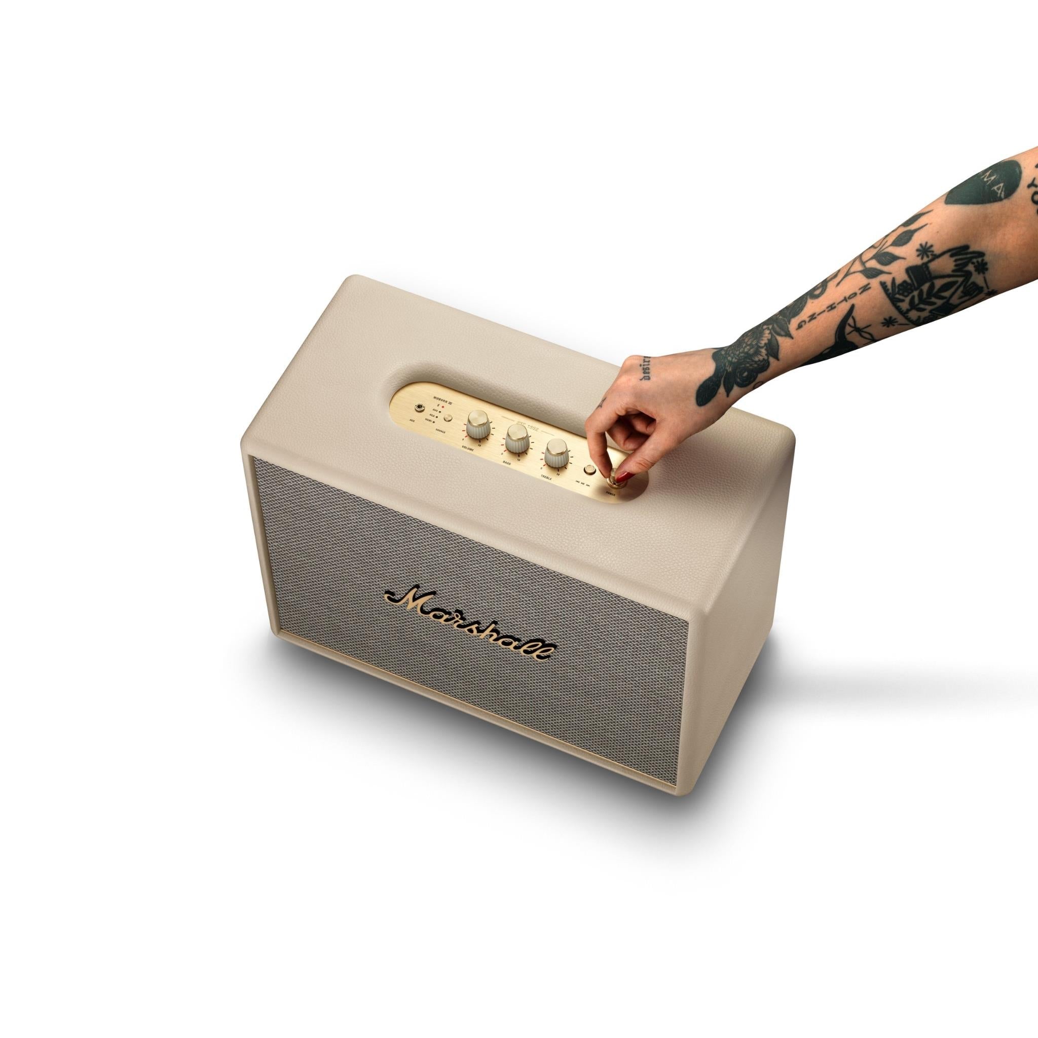 Cream Bluetooth speaker being adjusted by hand