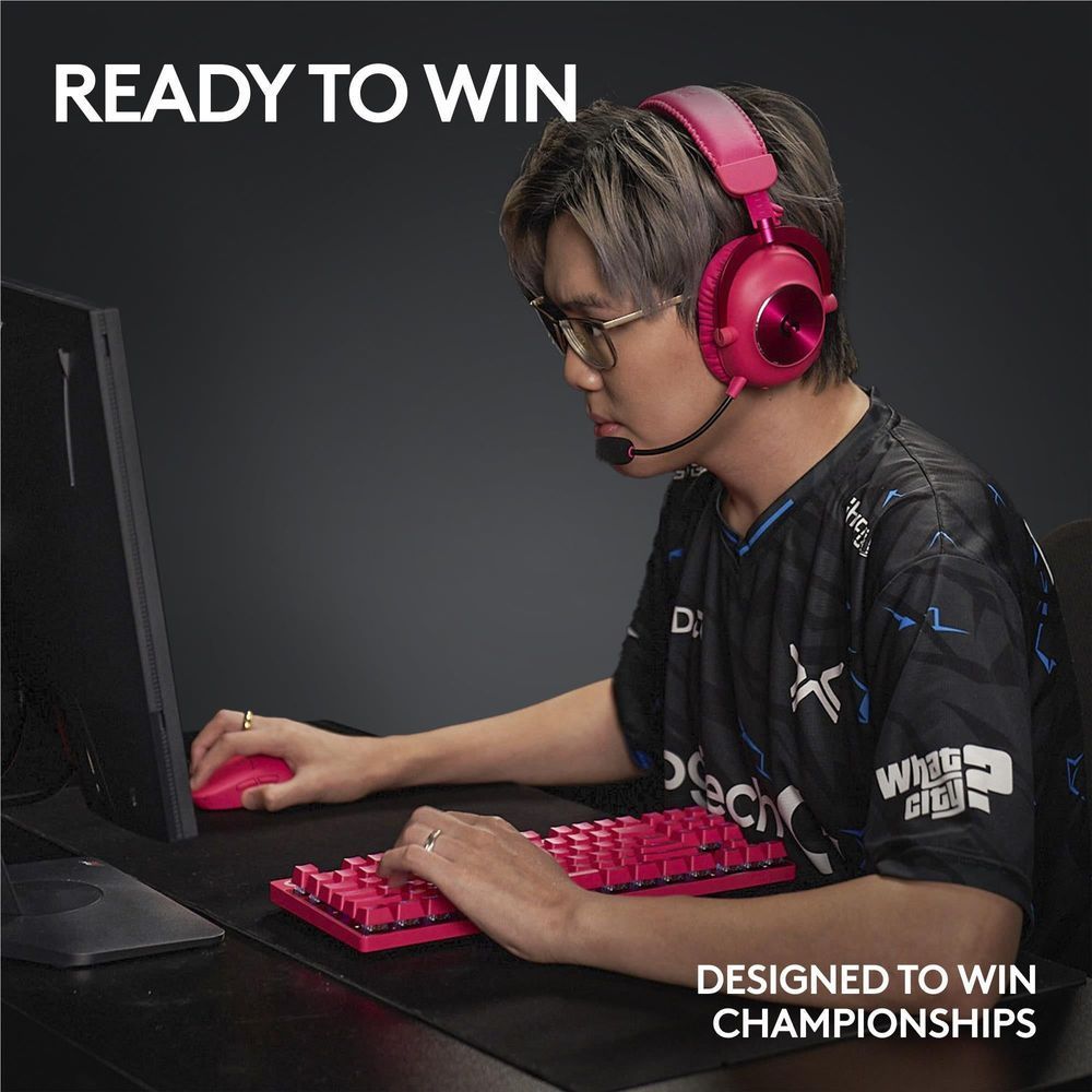 Magenta wireless gaming mouse in use during gameplay beside a red keyboard