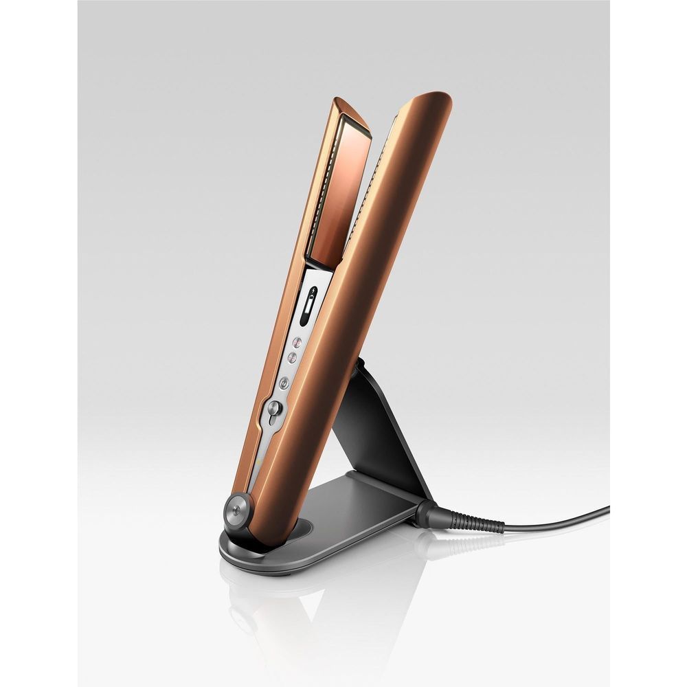 Copper and nickel cordless hair straightener standing on charging dock