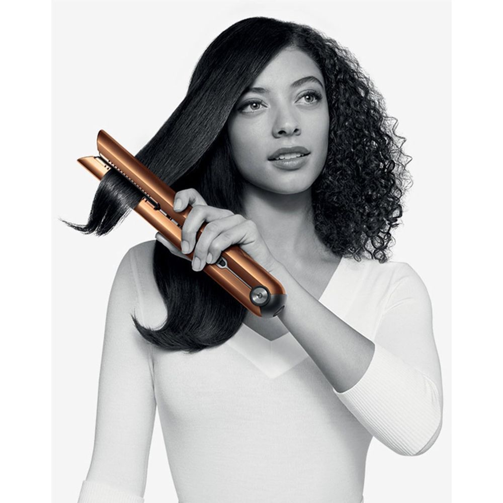 Copper and nickel cordless hair straightener creating smooth style on dark curls