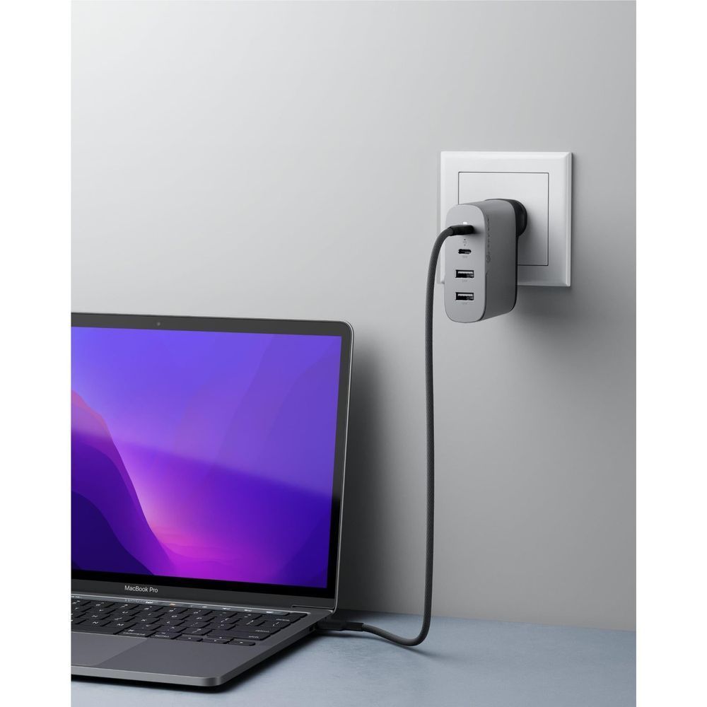 Space grey 4-port GaN charger plugged into wall outlet with USB cables