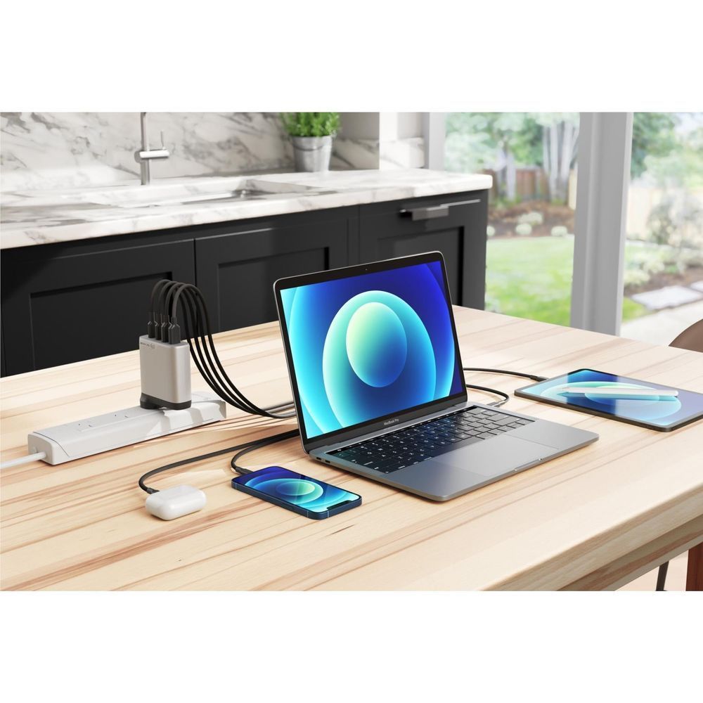 Space grey 4-port GaN charger on desk with USB cable connected to laptop