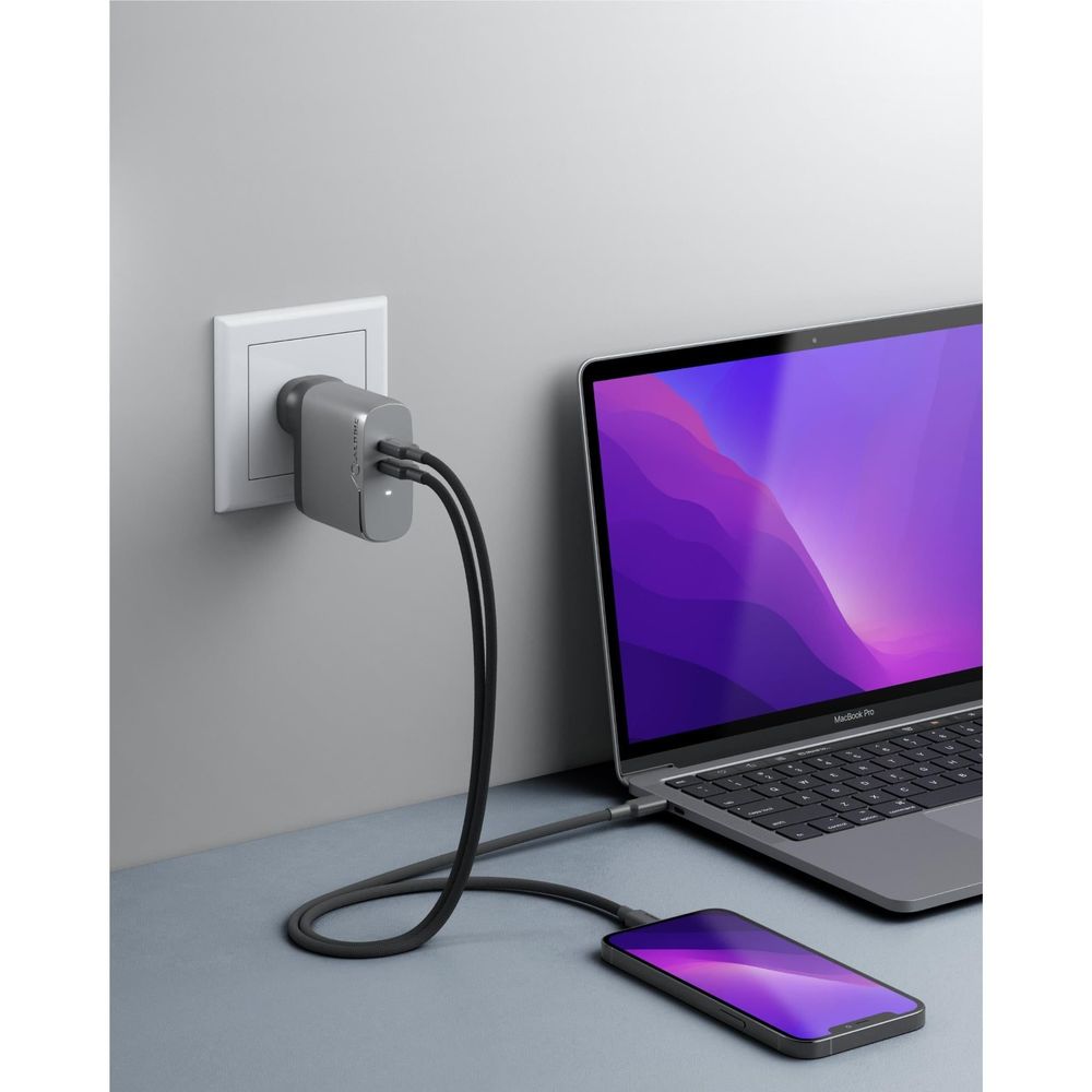 Space grey two-port GaN charger plugged into wall with charging cables