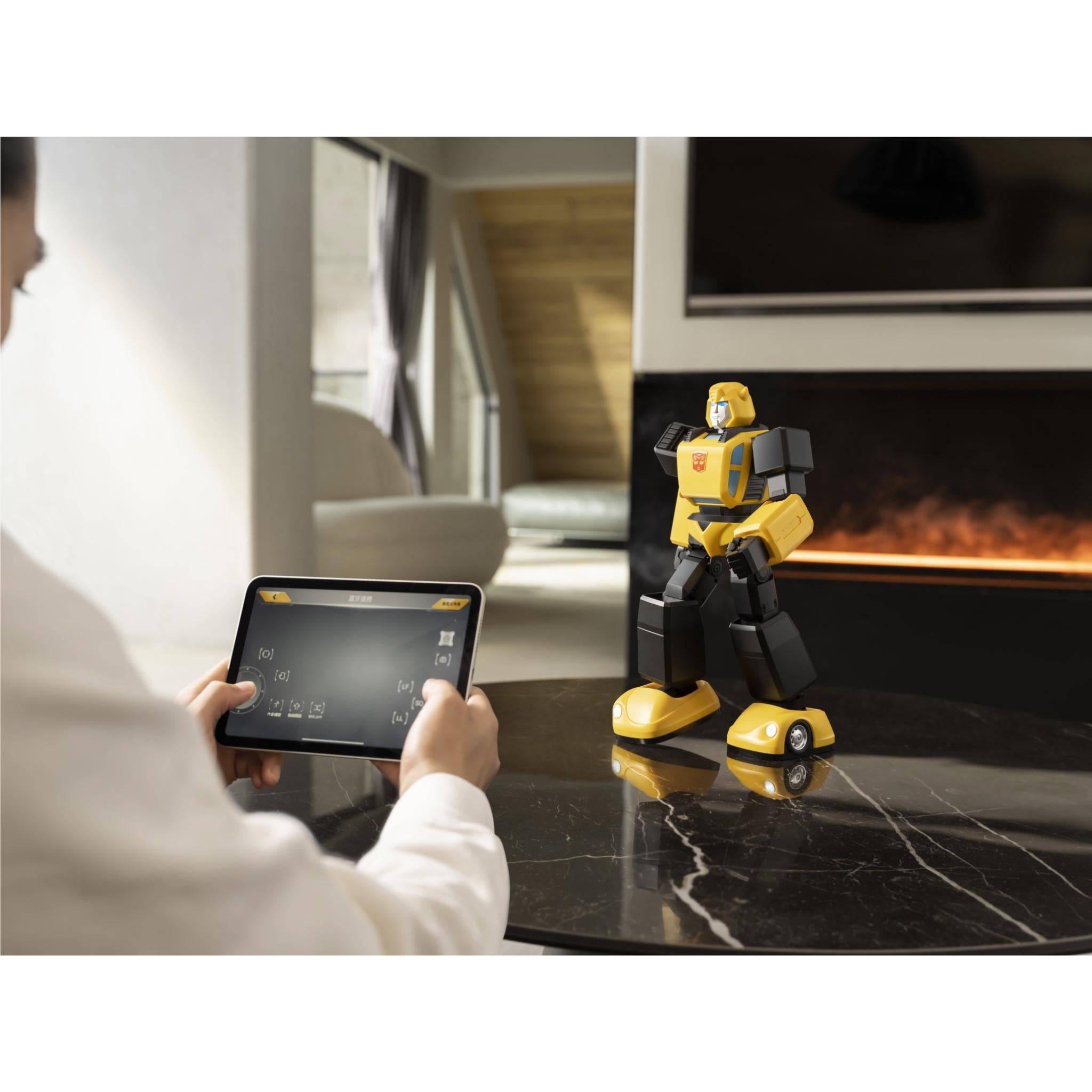 Yellow and black Bumblebee transformer robot on table while tablet controller is held