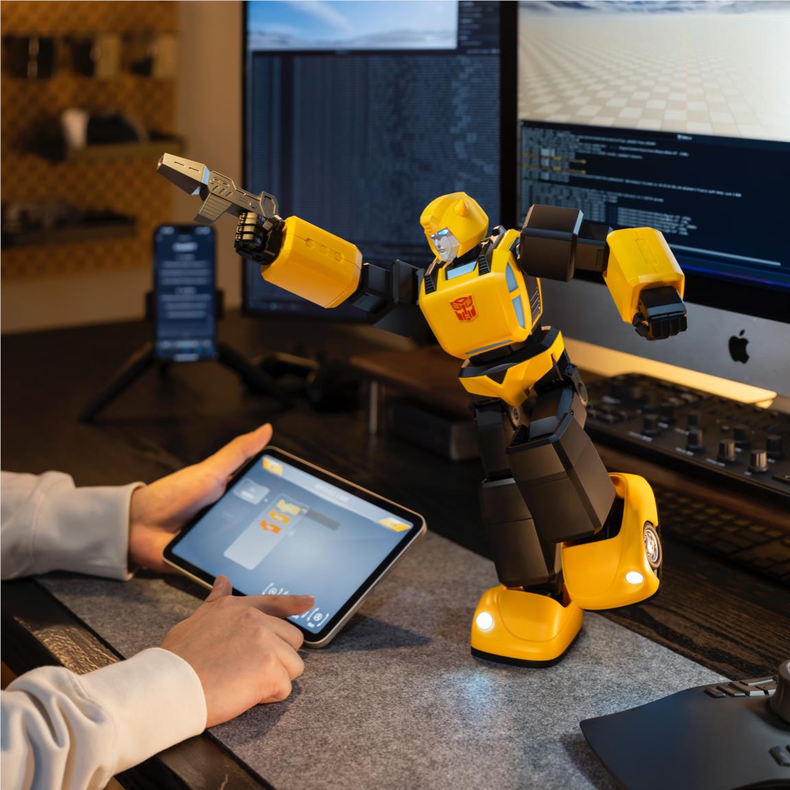Bumblebee transformer robot collectible on floor, near tablet and hands at desk