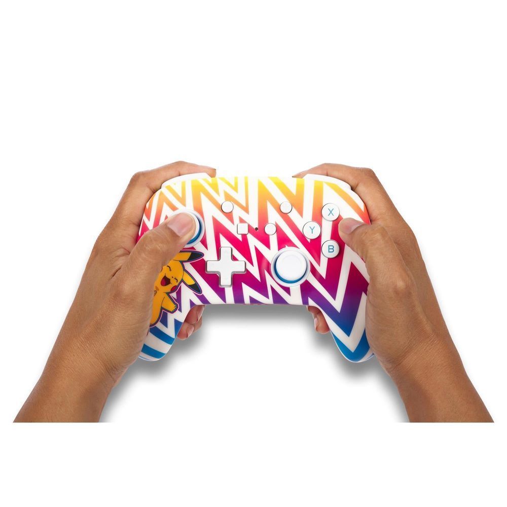 Hands holding white wireless controller with Pikachu zigzag artwork and colored face buttons